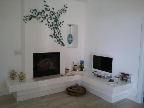 カルロフォルテにあるVilla Biancalunaの白いリビングルーム(暖炉、テレビ付)