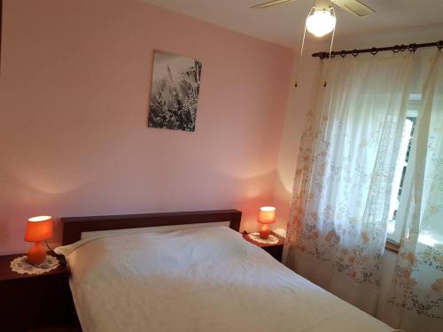 1 dormitorio con 1 cama con 2 lámparas y una ventana en Apartments Eli, en Korčula