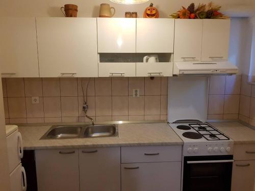 cocina con armarios blancos, fregadero y fogones en Apartments Eli, en Korčula