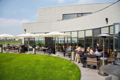 a group of people sitting at tables outside of a building at MG Restaurace/Luxury Apartments in Mladá Boleslav