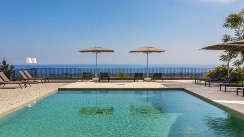 a swimming pool with chairs and umbrellas and the ocean at Talè Restaurant & Suite in Piedimonte Etneo