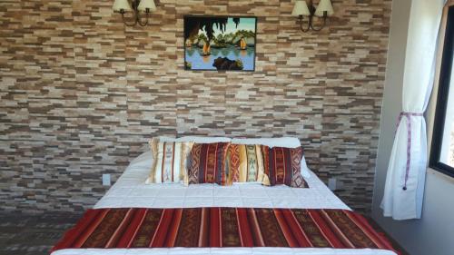 1 cama en un dormitorio con pared de ladrillo en Sol de Elefantes, en Villa Serrana