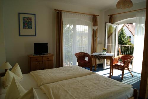 a bedroom with a bed and a table and a balcony at Pension Waldeck in Göhren