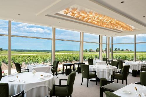 une salle à manger avec des tables et des chaises blanches et des fenêtres dans l'établissement Château Lafaurie-Peyraguey Hôtel & Restaurant LALIQUE, à Bommes