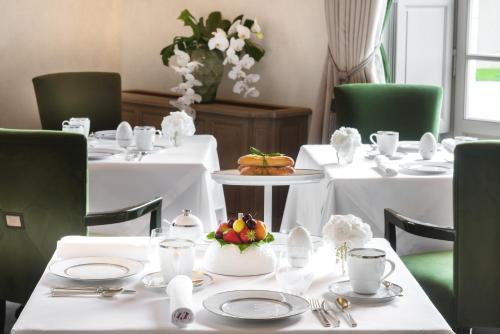 Un comedor con mesas blancas y sillas verdes. en Château Lafaurie-Peyraguey Hôtel & Restaurant LALIQUE, en Bommes