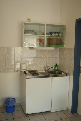 eine Küche mit weißen Schränken und einem Waschbecken in der Unterkunft Pension Waldeck in Göhren