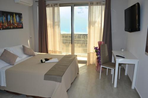 a bedroom with a bed and a desk and a window at B&B Varadero in Milazzo