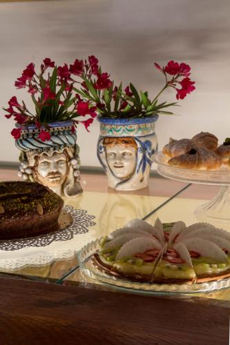 a glass table with plates of food and vases with flowers at Villa Felicia in Noto