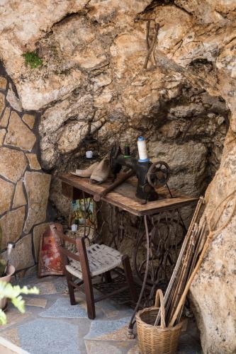 a table and a chair in front of a stone wall at Manthiata Studios in Exanthia