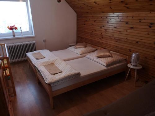 two beds in a room with a wooden wall at Ubytovanie v súkromí na Liptove in Liptovský Ján