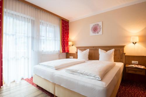 a bedroom with a large white bed and a window at Alpenchalet Brücke in Mayrhofen