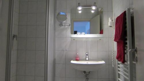 La salle de bains est pourvue d'un lavabo et d'une douche avec un miroir. dans l'établissement Hotel Zum Schwarzen Bär, à Hermsdorf