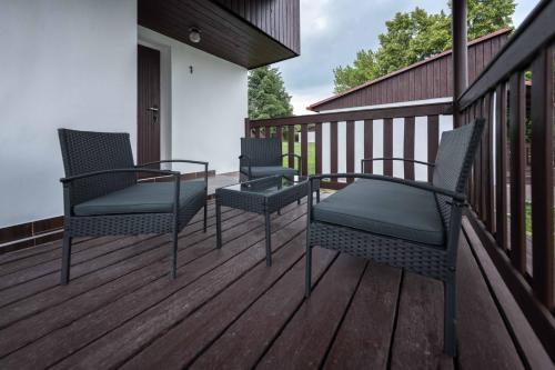 two chairs and a table on a deck at Chaty a Apartmány Hracholusky Kemp Kosatka in Pňovany