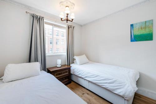 a bedroom with two beds and a window at Prime London Apartment, Oxford Circus in London