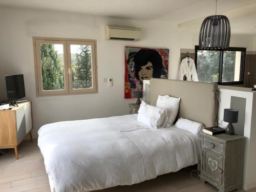 PujautにあるMaison proche d'Avignonのベッドルーム1室(大きな白いベッド1台、窓2つ付)