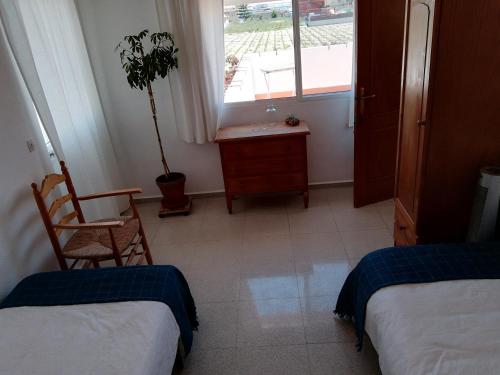 a room with two beds and a table and a window at Casa Algaida in Sanlúcar de Barrameda