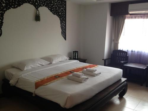 a bedroom with a large bed with towels on it at Wangburapa Grand Hotel in Chiang Mai