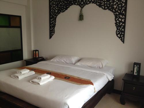 a bedroom with a bed with two towels on it at Wangburapa Grand Hotel in Chiang Mai