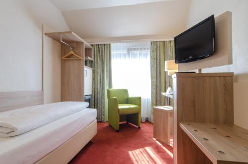 a hotel room with a bed and a flat screen tv at Garden Hotel in Nürnberg