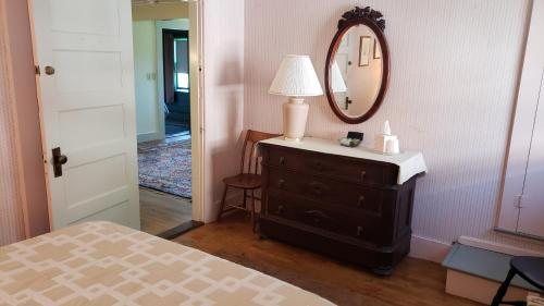 a bedroom with a dresser with a lamp and a mirror at Hawks House Inn in Walpole