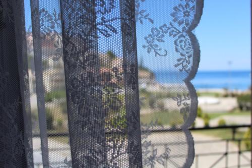 a view of a beach through a mesh window at Fissas Rooms in Sivota