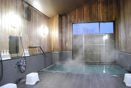 a large bathroom with a tub with a shower and a window at Hakuba Panorama Hotel in Hakuba