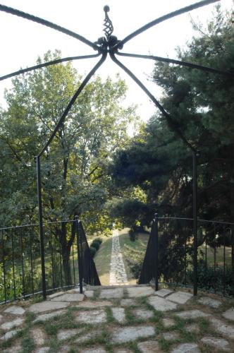 un ponte di metallo su una strada sterrata con alberi di Villa Bregana a Carnago