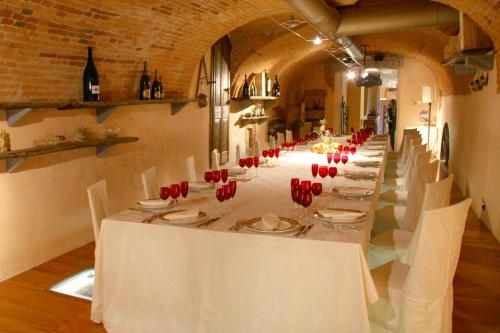 a long table in a room with white tables and red chairs at Villa Bregana in Carnago