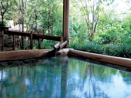 a pool with a water fountain in a garden at Yumoto Konpira Onsen Hananoyu Kobaitei in Kotohira