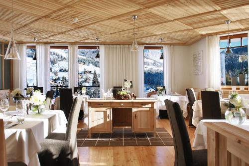 a dining room with tables and chairs and windows at Hotel La Majun in La Villa