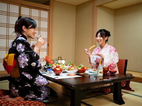 two women sitting at a table eating food at Yumoto Konpira Onsen Hananoyu Kobaitei in Kotohira