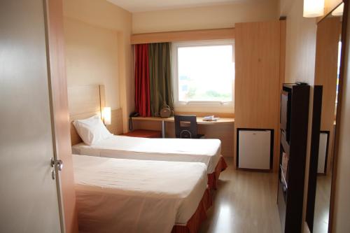 um quarto de hotel com duas camas e uma janela em ibis Vitoria da Conquista em Vitória da Conquista