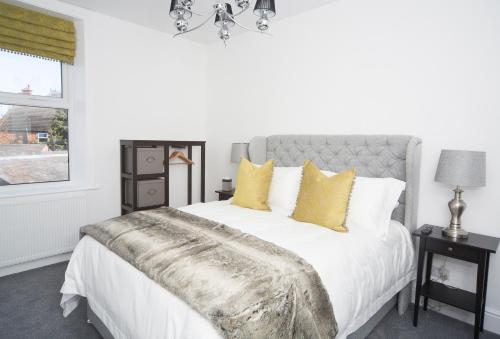 a bedroom with a white bed with yellow pillows at The Annex in Carlisle