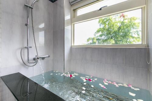 ein Bad mit einer Badewanne, einem Fenster und einer Dusche in der Unterkunft Saint Petersburg in Dongshan