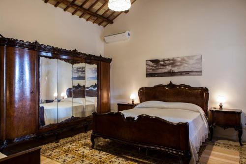 1 dormitorio con cama de madera y espejo grande en Sogno Siciliano Turismo Rurale, en Erice