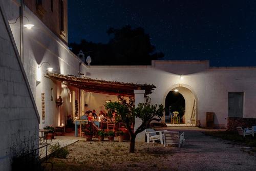 a group of people sitting outside of a building at night at Masseria Palombara Relais & SPA - Adults only in Manduria