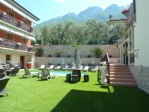 a yard with a pool and chairs and a building at Albergo Casa Este in Brenzone sul Garda