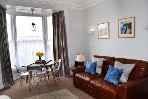 a living room with a leather couch and a table at Awel Mor Holiday Apartment in Aberystwyth
