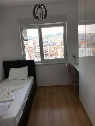 Un dormitorio pequeño con una cama y dos ventanas. en Cassiopeia Apartament, en Tirana