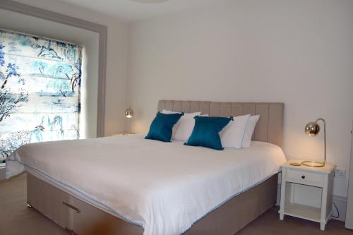 a bedroom with a large white bed with blue pillows at Awel Mor Holiday Apartment in Aberystwyth