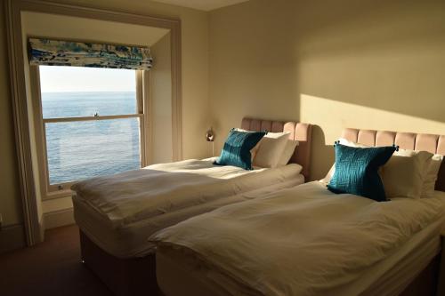 two beds in a hotel room with a window at Awel Mor Holiday Apartment in Aberystwyth