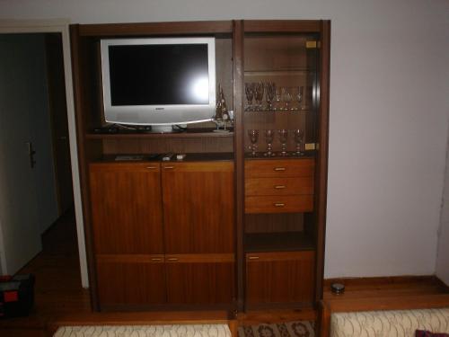 a wooden entertainment center with a television and wine glasses at Traditional House Paschalis in Kavala