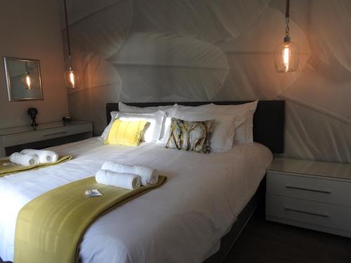 1 dormitorio con 1 cama blanca grande y toallas. en The Featherbed - Oudtshoorn, en Oudtshoorn