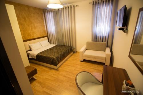 a small room with a bed and a chair at Hotel Flamingo in Korçë