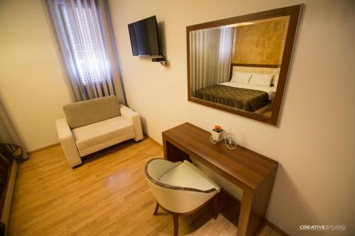 Habitación con cama, espejo y silla. en Hotel Flamingo, en Korçë