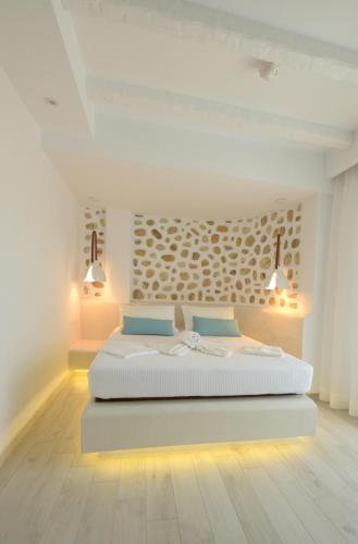 ein weißes Schlafzimmer mit einem Bett und zwei Lampen in der Unterkunft La Pierre in Limenaria