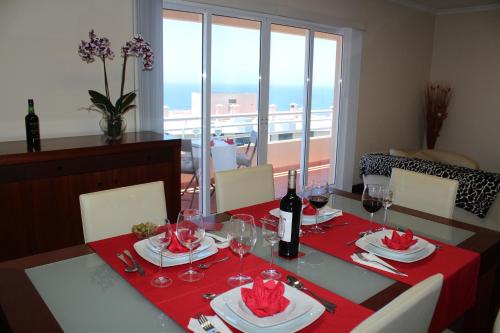 フンシャルにあるApartment José Colinas Lidoのダイニングルームテーブル(赤いテーブルクロス付)、ワイングラス