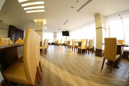 a dining room with chairs and tables and a television at SAS Al Olaya Hotel Aprtments in Al Khobar