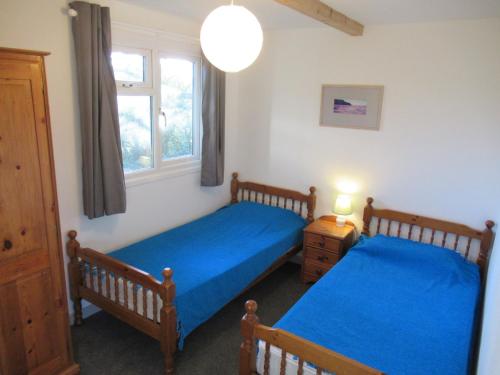 een slaapkamer met 2 bedden en een raam bij Mount Hawke Holiday Bungalows in Porthtowan