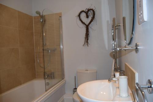 a bathroom with a sink and a shower with a heart on the wall at Awel Mor 3 Luxury Apartment in Aberystwyth